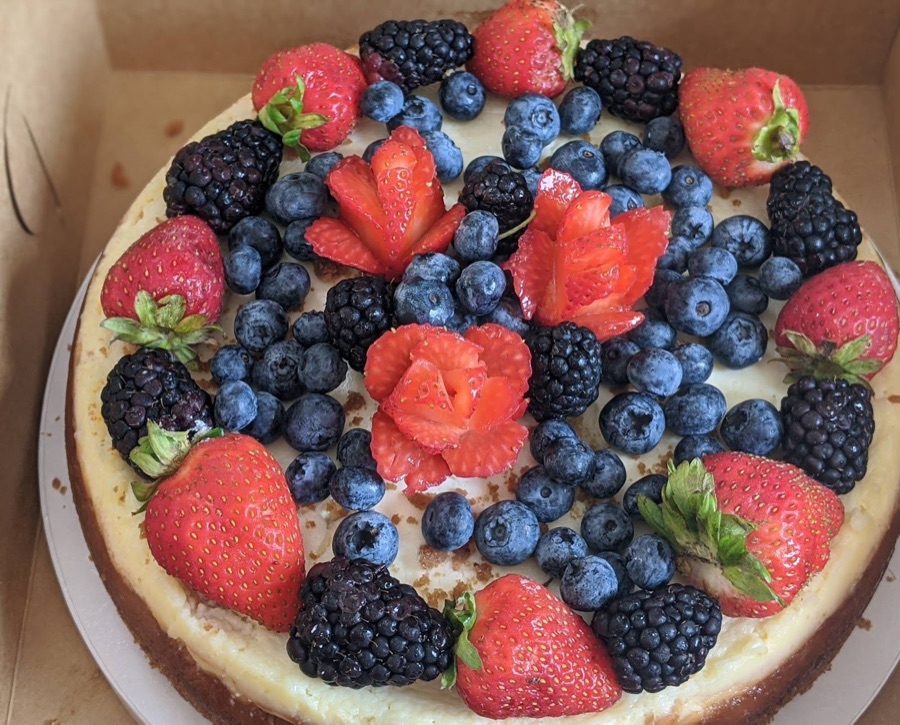 A cheesecake covered in strawberries, blueberries and blackberries