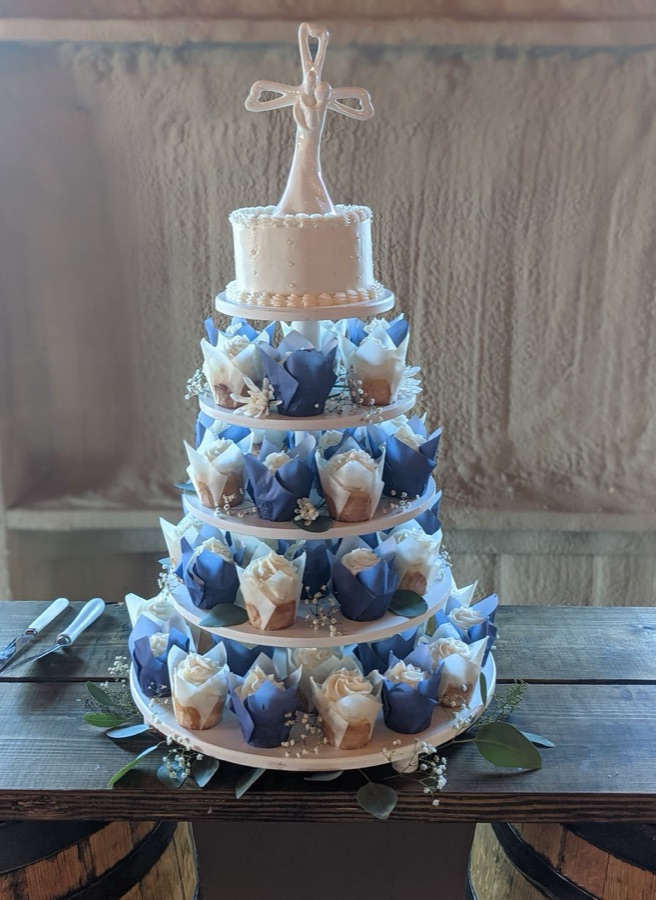 A tiered tower of navy blue cupcakes with white frosting