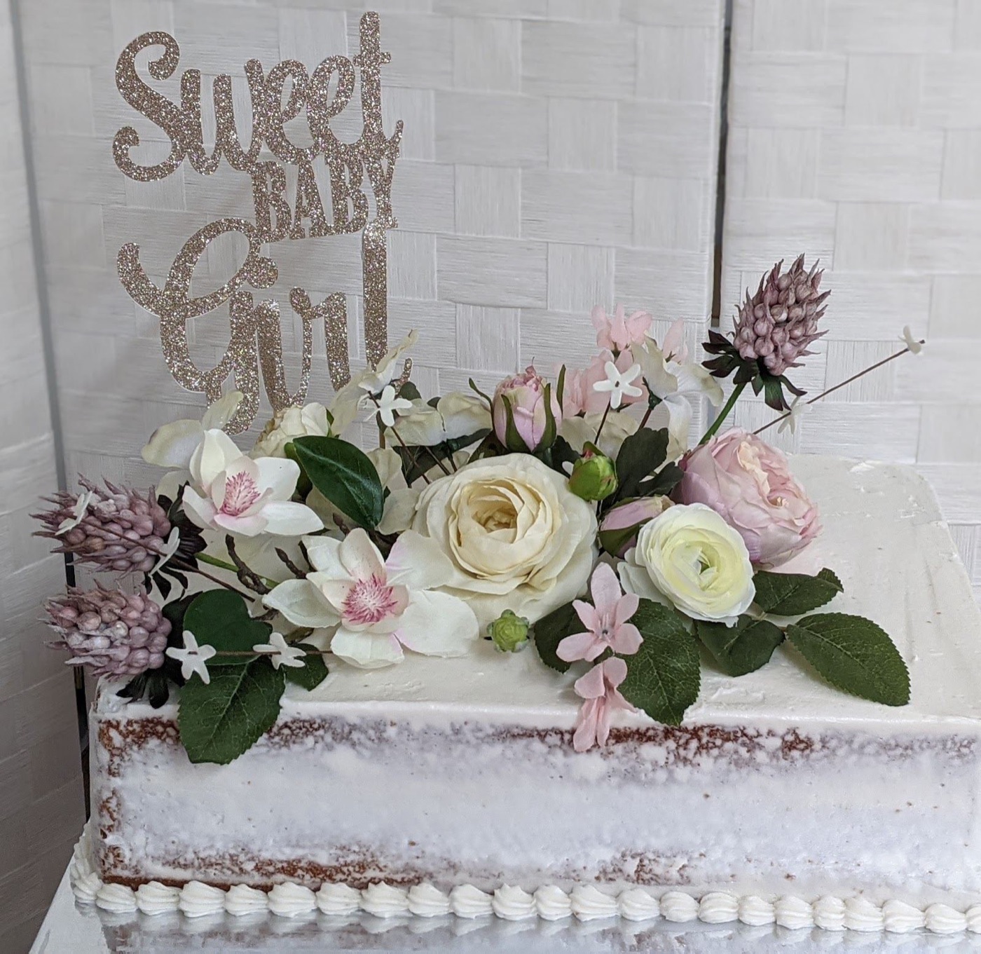 A white wedding cake covered in blush and white sugar flowers