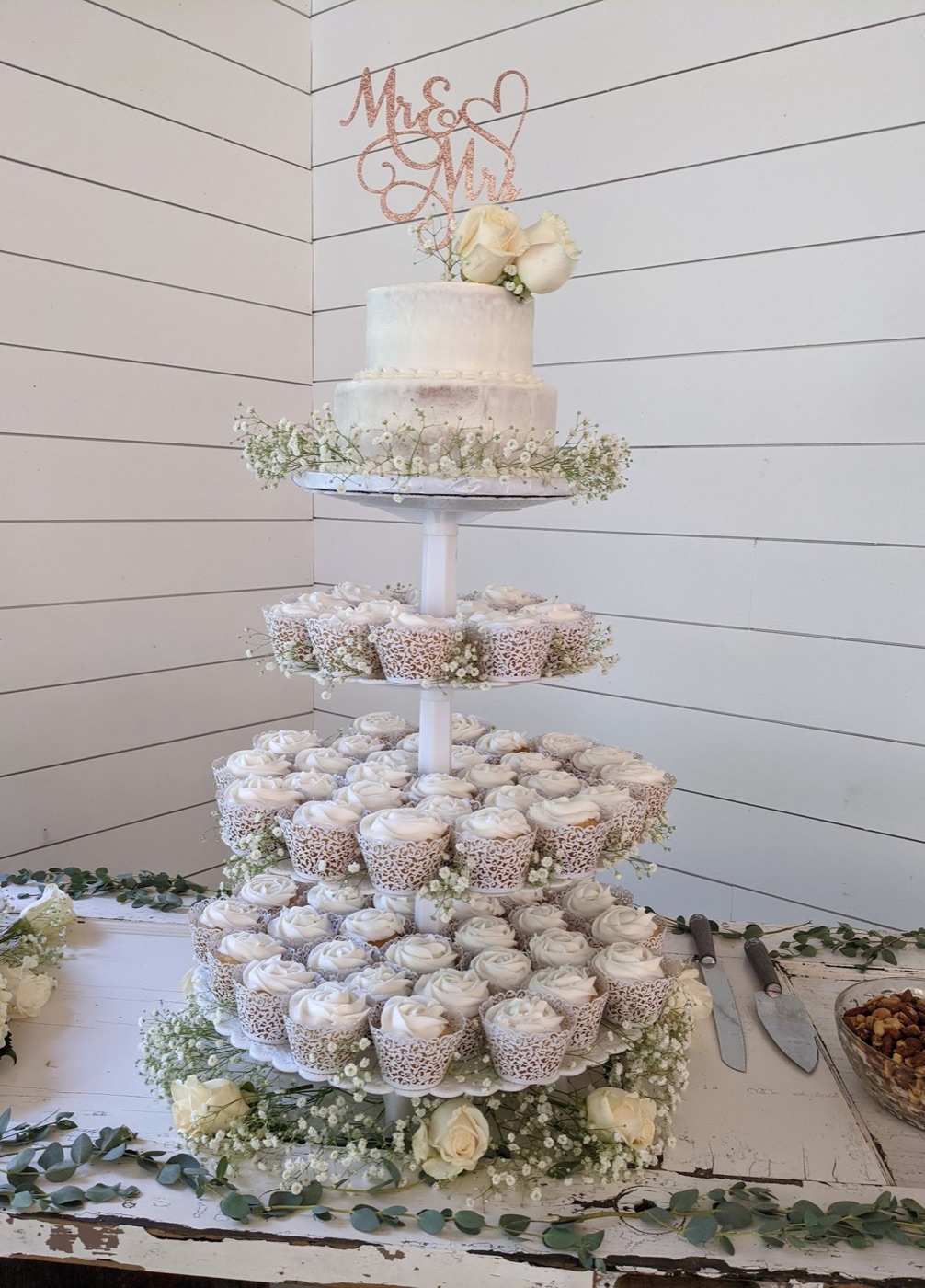 A tall white cupcake tower with a small cutting cake on top